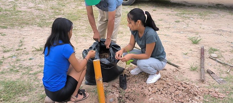 Two girls planting a tree in Chazuta as part of a reforestation project with the ecological group Chuya Chuya