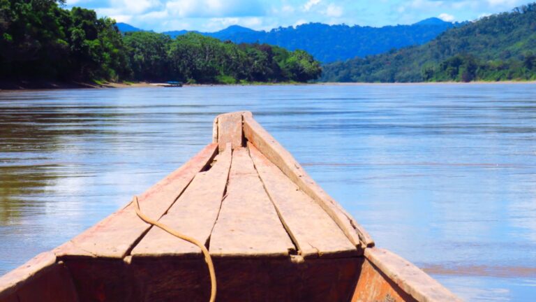 Wooden native canoe sailing down the Huallaga river in the Amazon rainforest, Peru